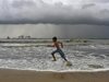 A boy runs as he plays on a beach against the background of pre-monsoon clouds gathered over the Arabian Sea at Kochi in Kerala